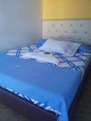 a bed with a blue comforter and a pillow at Hotel Oiba Alfa Plaza in Oiba