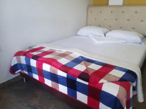 a bed with a red white and blue checkered blanket at Hotel Oiba Alfa Plaza in Oiba