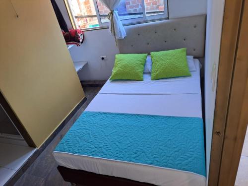 a small bed in a small room with green pillows at Hotel Oiba Alfa Plaza in Oiba