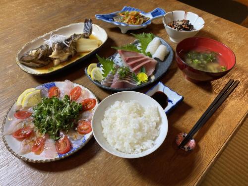 a table with plates of food and bowls of rice at guesthouse碧 in Okinoshima
