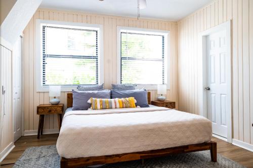 a bedroom with a large bed and two windows at Mid-Century 1bd House - Beach Gear - 5min Walk to Beach in Clearwater Beach