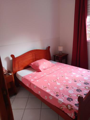 a bedroom with a bed with a pink comforter at Pagerie bas de villa in Les Trois-Îlets