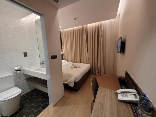 a bathroom with a bed and a sink and a toilet at Wink Hotel @ Bugis in Singapore