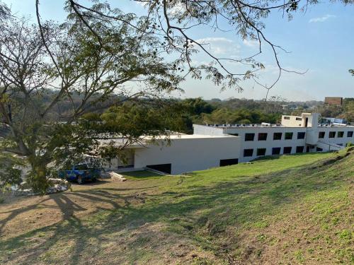 a white building on a hill next to a field at LOS BAMBUES HOTEL in La Tinaja