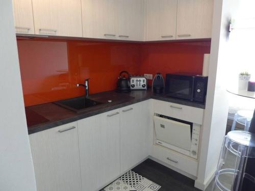 une petite cuisine avec un évier et un micro-ondes dans l'établissement superbe studio MIRAMAR plein sud, pieds dans l'eau, à Biarritz