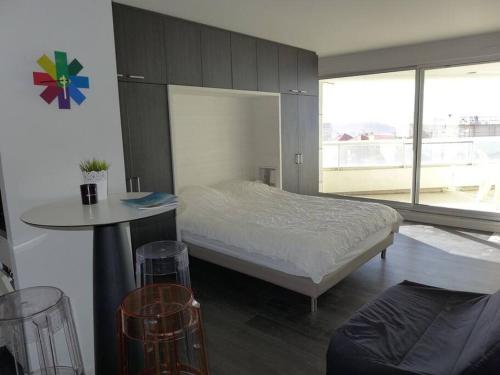 une chambre avec un lit, une table et une fenêtre dans l'établissement superbe studio MIRAMAR plein sud, pieds dans l'eau, à Biarritz