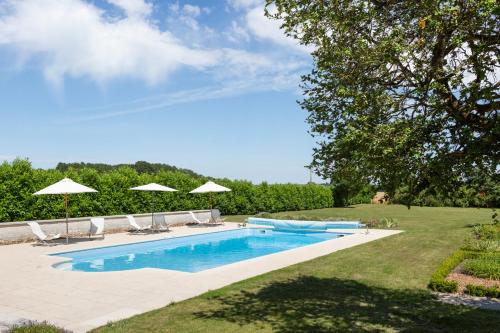 une piscine avec chaises et parasols dans une cour dans l'établissement Chateau De Grazay, à Chaveignes