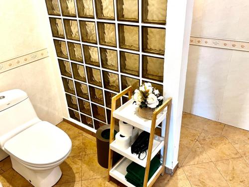a bathroom with a toilet and a shelf with flowers at Villa Malee in Thai Muang