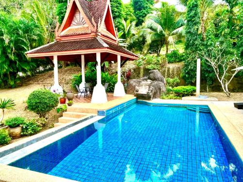 a swimming pool with a gazebo next to a resort at Villa Malee in Thai Muang