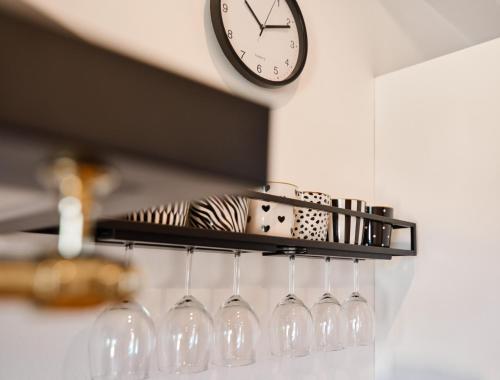 a shelf with wine glasses and a clock on a wall at Lipowy Zakątek - domki blisko Energylandii i stacji PKP w Zatorze in Zator