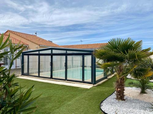 un poolhouse avec des portes en verre et un palmier dans l'établissement Maison Lumineuse avec Piscine Privée près de la Plage - Longeville-sur-Mer - FR-1-336-151, à Longeville-sur-Mer