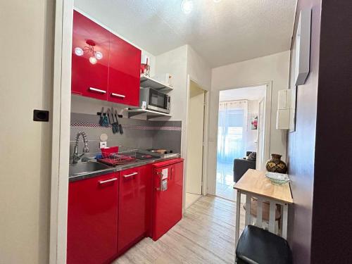 une petite cuisine avec des placards rouges et une table dans l'établissement Studio 4 Pers, Plage à 800m, Centre Cannes la Bocca, Ascenseur, Wifi Gratuit - FR-1-609-99, à Cannes