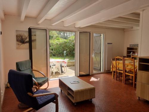 un salon avec des chaises et une table ainsi qu'une chambre dans l'établissement Villa à Seignosse: Plage à pied, Terrasse, 3 Chambres, Quartier calme - FR-1-239-1036, à Seignosse
