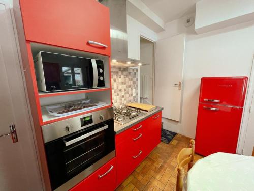 - une cuisine rouge avec cuisinière et four micro-ondes dans l'établissement Confort et Charme au Cœur de Loches - Gîte Tout Inclus avec Cour et Parking - FR-1-381-572, à Loches