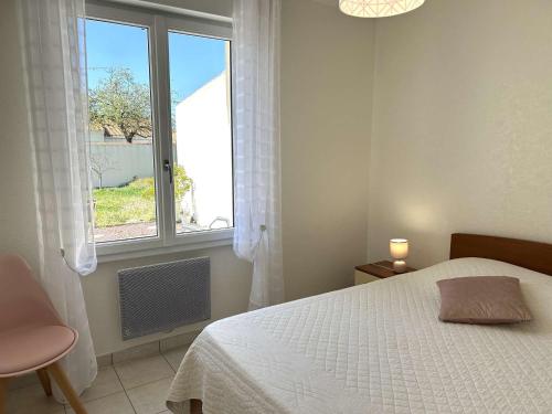 une chambre avec un lit et une grande fenêtre dans l'établissement Maison de plain-pied avec jardin clos, véranda, terrasse et barbecue, près de St Gilles Croix de Vie - FR-1-224-811, à Le Fenouiller
