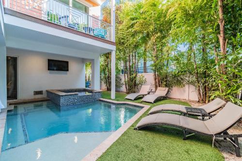 un patio trasero con piscina y tumbonas en Playa Esmeralda Vacation Home Up To 14 People, en Bradenton Beach