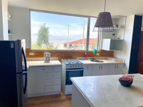 eine Küche mit einem Kühlschrank und einem Fenster in der Unterkunft ¡Fogata y Lujo! in Ambato
