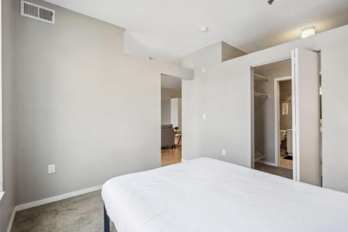 a bedroom with white walls and a white bed at CozySuites Mill District with pool, gym #01 in Minneapolis