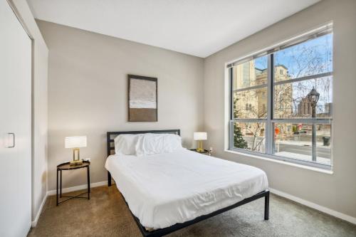 a bedroom with a bed and a large window at CozySuites Mill District with pool, gym #01 in Minneapolis
