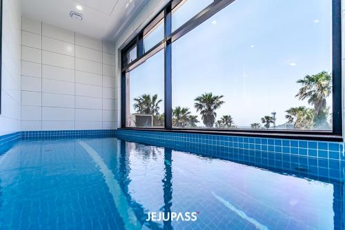 an indoor swimming pool with blue tiles and windows at Liverpool & Spa in Jeju