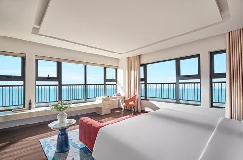 ein Hotelzimmer mit einem großen Bett und großen Fenstern in der Unterkunft Vias Hotel Vung Tau - Inclusive Transportation in Vũng Tàu