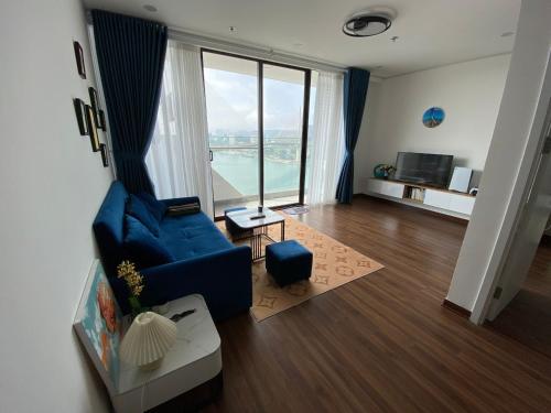 ein Wohnzimmer mit einem blauen Sofa und einem großen Fenster in der Unterkunft Green Diamond Homestay in Hạ Long