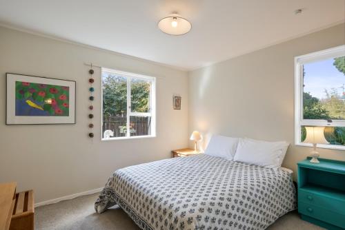 um quarto com uma cama e duas janelas em Olive Terrace - Paraparaumu Holiday Home em Paraparaumu