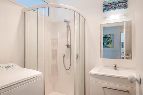 uma casa de banho branca com um chuveiro e um lavatório. em Olive Terrace - Paraparaumu Holiday Home em Paraparaumu