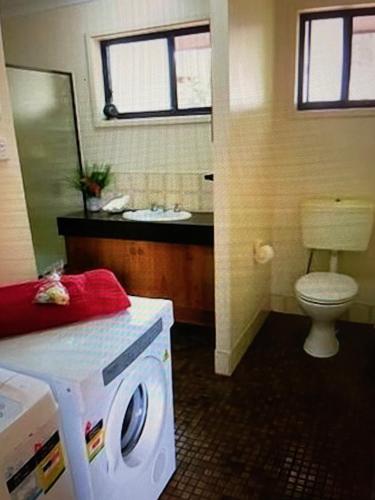 a bathroom with a toilet and a washing machine at Absolute Beachfront Mollymook in Mollymook