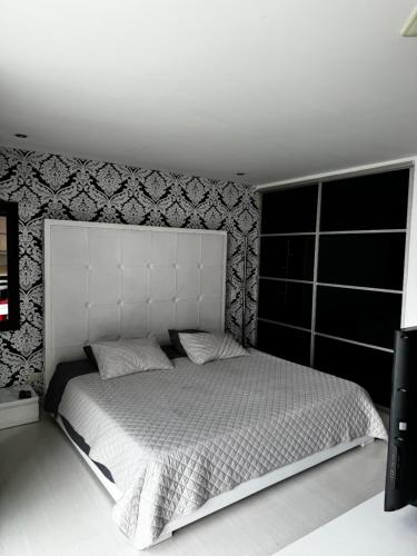 a bedroom with a white bed with a large headboard at Blux 1305 Poblado Medellín Colombia in Medellín