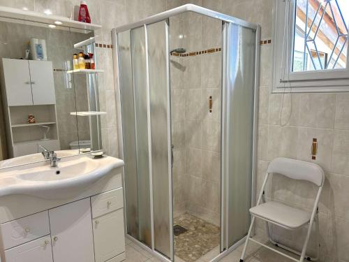 La salle de bains est pourvue d'une douche, d'un lavabo et d'une chaise. dans l'établissement Maison de plain-pied avec jardin clos, véranda, terrasse et barbecue, près de St Gilles Croix de Vie - FR-1-224-811, à Le Fenouiller