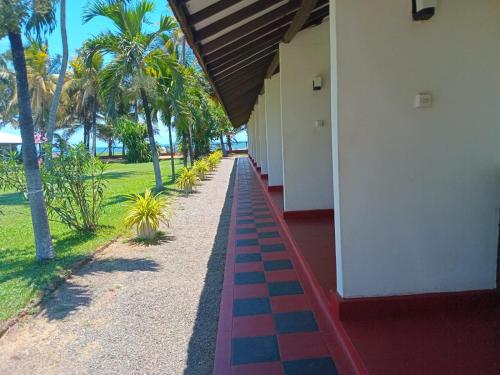 a building with a pathway with palm trees in the background at Ceylonica Beach Hotel in Negombo
