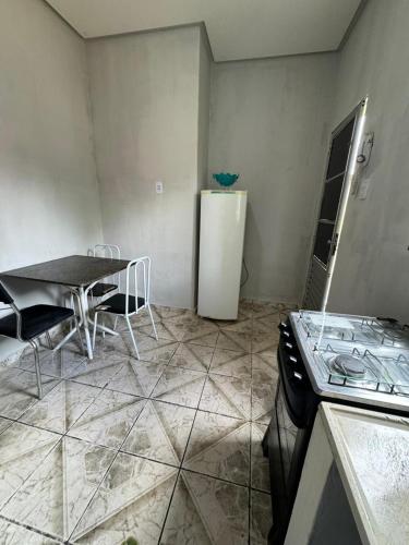 eine Küche mit einem Tisch und einem weißen Kühlschrank in der Unterkunft Kitnet mobiliada em Parauapebas in Parauapebas
