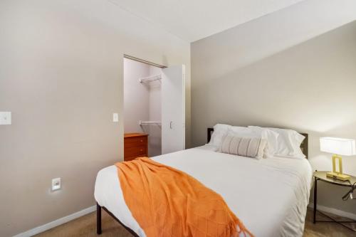 Un dormitorio con una cama blanca con una manta naranja. en CozySuites Mill District pool gym # 05, en Minneapolis