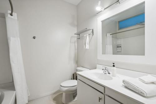 a white bathroom with a sink and a toilet at CozySuites Mill District pool gym # 03 in Minneapolis