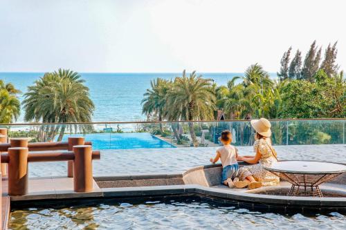 zwei Personen sitzen auf einer Couch neben einem Pool in der Unterkunft DoubleTree by Hilton Shanwei in Shanwei