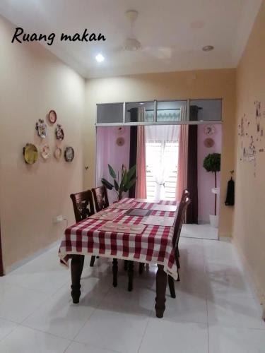a dining room table with a checkered table cloth on it at Homestay Noor Mak Lagam in Kemaman