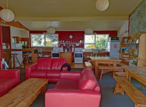 Punakaiki Beach Hostel في بوناكايكي: غرفة معيشة بأثاث احمر ومطبخ
