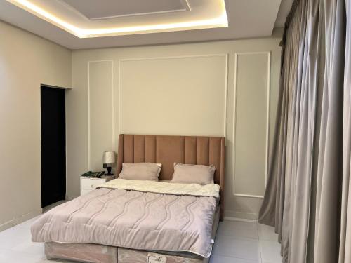 a bedroom with a bed with a wooden headboard at شاليه جود in Riyadh