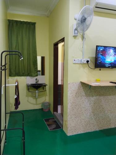 a room with a fan and a green floor at Fadlim Homestay in Padang Serai