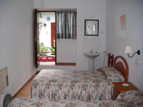 um quarto com 2 camas, um lavatório e uma janela em Pensión San Andrés I em Jerez de la Frontera