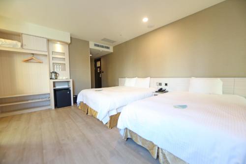 two beds in a hotel room with white sheets at Grand Earl Hotel in Douliu