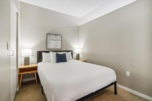 1 dormitorio con 1 cama blanca grande y 2 lámparas en CozySuites Mill District pool gym # 04 en Minneapolis