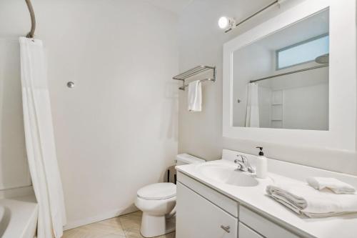 a white bathroom with a sink and a mirror at CozySuites Mill District pool gym # 04 in Minneapolis