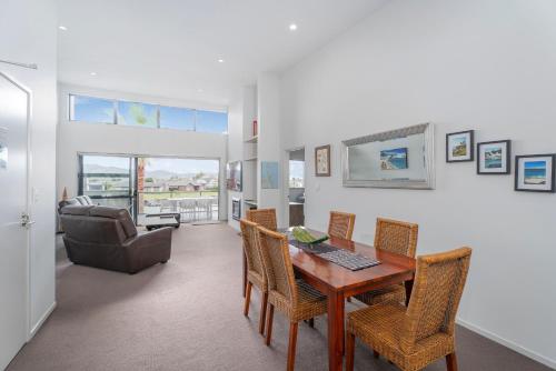 a living room with a table and chairs and a couch at Sovereign Pier On The Waterways in Whitianga
