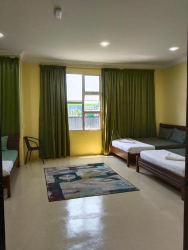 a bedroom with two beds and a window with green curtains at Fadlim Homestay in Padang Serai