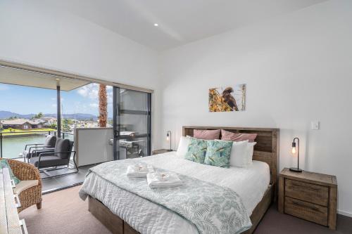a bedroom with a large bed and a balcony at Sovereign Pier On The Waterways in Whitianga