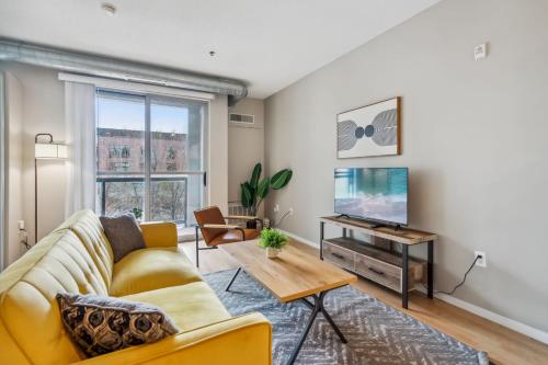 a living room with a yellow couch and a tv at CozySuites Mill District with gym #06 in Minneapolis