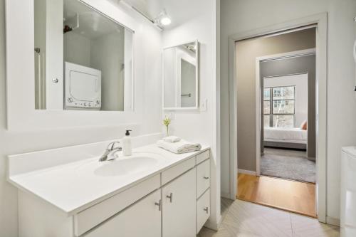 a white bathroom with a sink and a mirror at CozySuites Mill District pool gym # 08 in Minneapolis