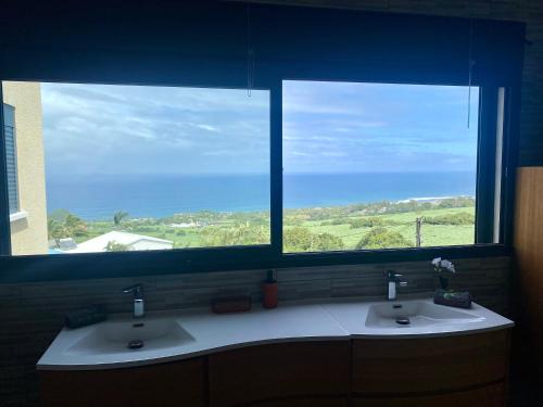 two sinks in a bathroom with two windows at La Villa Des Oliviers in Petite Île